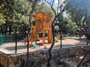 a wooden playground in a park next to a stone wall at Blue Penguin in Pinezici
