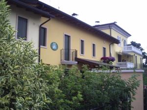a yellow house with a balcony and bushes at Corte Nuova in Valeggio sul Mincio