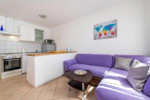 a living room with a purple couch and a kitchen at Azzuro in Baška