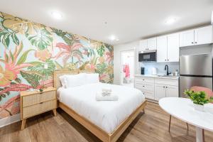 1 dormitorio con 1 cama grande y papel pintado tropical en Pastel Tropics Studio Apartment, en Galveston