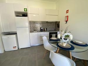 a kitchen with a table and chairs and a refrigerator at Casa com terraço e piscina Sagres in Sagres
