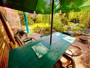 una mesa de picnic verde con una sombrilla en un patio en Kwatera prywatna na Kaszubach, 