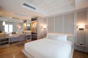 Schlafzimmer mit einem großen weißen Bett und einem Schreibtisch in der Unterkunft K Maison Boutique Hotel in Bangkok