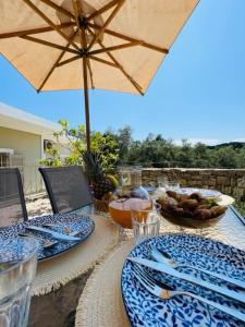 een tafel met blauwe en witte borden en een paraplu bij Ellie’s House in Lákka