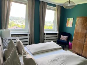 a bedroom with two beds in front of two windows at Ferienwohnung mit traumhaftem Seeblick in Velden am Wörthersee