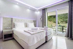 a white bedroom with a large bed and a balcony at Villa Dionysia Studio S7 in Alikanas +19 photos