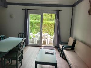 uma sala de estar com um sofá, uma mesa e cadeiras em Village de 19 gites avec Piscine et restaurant, Grand Vabre Nature em Conques