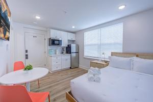 Cet appartement comprend une chambre avec un lit blanc, une table et une cuisine. dans l'établissement Surf Trip Studio Apartment, à Galveston