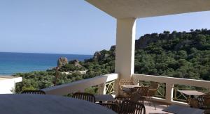 a balcony with tables and chairs and a view of the ocean at Polyrizos Hotel in Rodakino