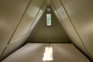 a bed in a small room with a window at Chatky Skalní mlýn Adršpach in Adršpach