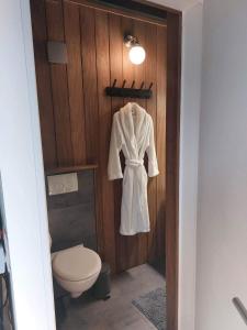 a white robe hanging on a wooden wall next to a toilet at Time 2 Relax chalet aan het water in Geel