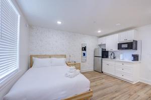 a bedroom with a large white bed and a kitchen at Tiger Motel Studio Apartment in Galveston