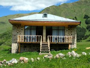 une maison en pierre avec un toit métallique sur une colline dans l'établissement Terkhena, à Kazbegi