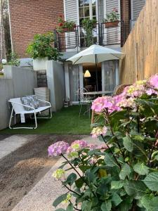 un patio con mesa, sombrilla y flores en A casa di Rachele, en Marina Romea