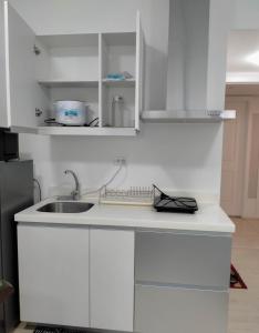 a kitchen with white cabinets and a sink at SM Bicutan Affordable Rooms in Manila