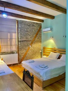 1 dormitorio con 2 camas y pared de ladrillo en Guest House Savane, en Gori