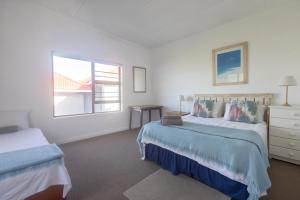 a white bedroom with two beds and a window at The Beauty of The Wildside in Cape St Francis