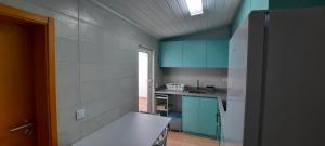 cocina con armarios verdes y encimera blanca en Casa Esmar, en Odemira
