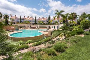 a swimming pool in a resort with palm trees at Luxury Apartment with Communal Pool and Terrace in Quarteira