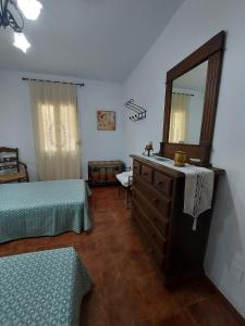 a bedroom with two beds and a dresser with a mirror at Casa Rural El Olivar Ronda in Arriate