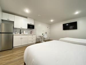 a white bedroom with a bed and a kitchen at Tropical Springs Studio Apartment Two Queen Beds in Galveston