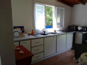 a kitchen with white cabinets and a sink and a window at Malaka Rose in Sainte-Rose