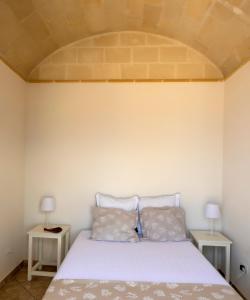 a bedroom with a white bed with two tables at Casa Conte Pio in Marettimo