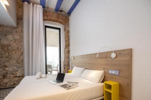 1 dormitorio con 1 cama con ordenador portátil en Tgna Cervantes 8, en Tarragona