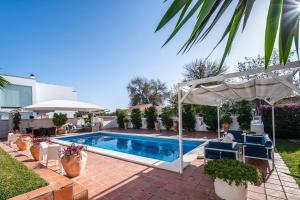 a swimming pool in a backyard with a white umbrella at Charming 10 person Villa in Sevilla in Tomares