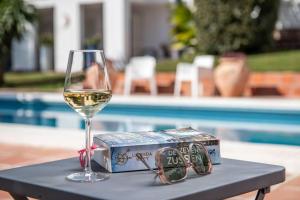 a glass of wine sitting on a table next to a box of wine at Charming 10 pers Villa with swimmingpool Sevilla in Tomares