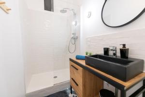 La salle de bains est pourvue d'un lavabo noir et d'une douche. dans l'établissement KASA BOHEME - Centre ville - Spacieux et tout équipé, à Saint-Étienne