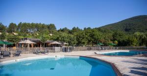 une piscine avec des chaises et une montagne en arrière-plan dans l'établissement Village Huttopia Dieulefit, à Dieulefit