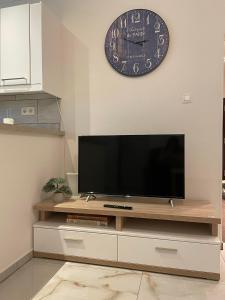 a flat screen tv sitting on a entertainment center with a clock at Apartment Nitra-city centre in Nitra