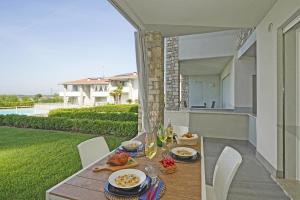 una mesa con comida y vino en un balcón con vistas a una casa en Le Mele 7 by Wonderful Italy, en Lonato