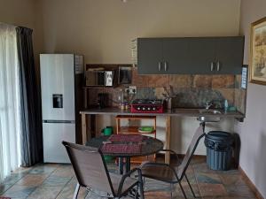 cocina con mesa, sillas y nevera en Votadini Country Cottages, en Magaliesburg