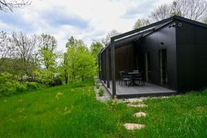 a black house with a deck in a field at Domki Karpatia BB in Bielsko-Biala +22 photos