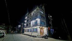 Un grand bâtiment blanc avec des lumières allumées la nuit dans l'établissement The Indian Kargil, à Kargil