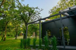 Domki Karpatia BB في بييلسكو بياوا: منزل أسود في حديقة مع أشجار