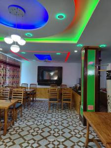 a restaurant with wooden tables and chairs and a flat screen tv at The Indian Kargil in Kargil