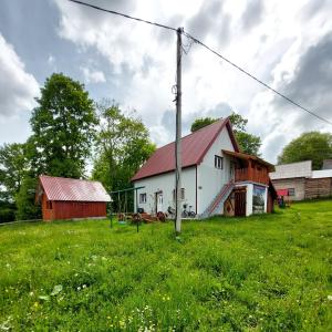 a white barn with a red roof in a field at Domaćinstvo Krstajić - Rural holiday in Žabljak