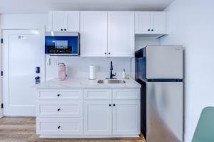 a kitchen with white cabinets and a refrigerator at Beverly Hills Studio Apartment 2 Queen Beds in Galveston +8 photos