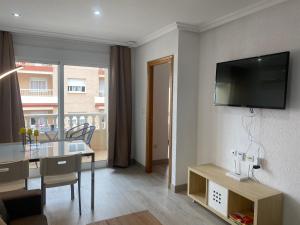 ein Wohnzimmer mit einem Tisch und einem TV an der Wand in der Unterkunft Homely Apartments Las Salinas in Torrevieja