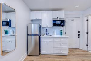 a kitchen with white cabinets and a stainless steel refrigerator at Roaring Tigers Studio Apartment in Galveston