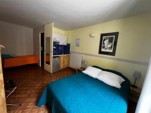 1 dormitorio con 1 cama azul y cocina en Le Vieux Château en Aiguines