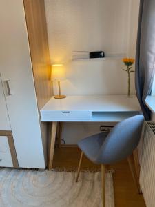 a desk with a blue chair and a lamp at Privatquartier im Ortskern von Westerstede in Westerstede