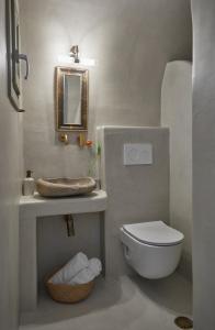 a bathroom with a toilet and a sink and a mirror at Arvanitis Cave Village in Akrotiri