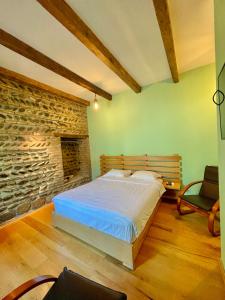 1 dormitorio con cama y pared de piedra en Guest House Savane, en Gori