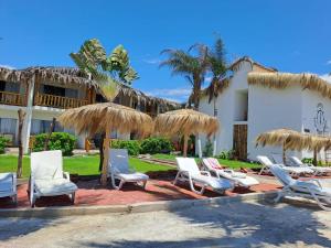 a group of chairs and umbrellas in front of a building at Hotel Casa Mediterranea Mancora in Máncora