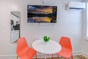 - une cuisine avec une table blanche et deux chaises orange dans l'établissement In Living Coral Studio Apartment, à Galveston