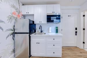  La cuisine est équipée de placards blancs et d'un réfrigérateur. dans l'établissement In Living Coral Studio Apartment, à Galveston